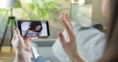 Kadın, evde yatakta yatan mutlu Afrikalı Amerikalı kıvırcık kızla görüntülü görüşme yapıyor. Kadın, odada otururken akıllı telefondan arkadaşıyla çevrimiçi görüntülü konuşma yapıyor. Boş zaman konsepti