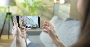 Odada oturan bir kadın oldukça heyecanlı beyaz, neşeli bir kızla görüntülü konuşma yapıyor. Video sohbet konseptinde yürüyen neşeli bir arkadaşla akıllı telefondan konuşan bir kadın.