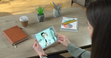 Odada otururken erkek doktorla görüntülü konuşma yapan bir kızın omuzlarının üstünden. Bir kadın video konferansında doktorla tıbbi görüşmeler yapıyor. Sağlık hizmetleri kavramı
