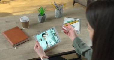Odada otururken erkek doktorla videolu sohbet eden bir kızın omuz manzarası. Yakışıklı beyaz doktor video konferansı aracılığıyla tıbbi danışmanlık yapıyor. Sağlık hizmetleri kavramı