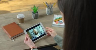 Masada otururken yakışıklı beyaz bir adamla görüntülü konuşma yapan bir kız. Kadın, karantinadaki erkek arkadaşıyla tablet üzerinde video konferansında sohbet ediyor. Video sohbet konsepti