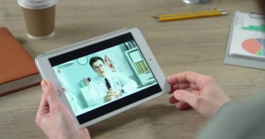 Odada otururken erkek doktorla görüntülü konuşma yapan bir kız. Kadının kapalı alanda doktorla yaptığı video görüşmelerini yakından takip edin. Sağlık hizmetleri kavramı