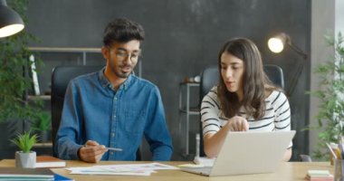 Gözlüklü genç bir Arap ve ofiste masasında oturan beyaz bir kız başlangıç projesi üzerinde birlikte çalışıyorlar. Karışık ırk erkek ve kadın iş arkadaşları iş ve belgeleri inceliyor..