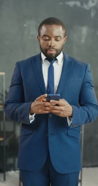 Afro-Amerikalı genç, neşeli iş adamı akıllı telefondan mesaj atıyor. Cep telefonuna kayan yakışıklı bir erkek. Takım elbiseli ve kravatlı adam neşeyle gülümsüyor. Hikayeler için dikey görüntüler