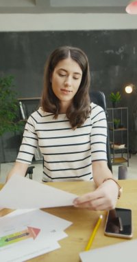 Beyaz, genç ve güzel bir kadın kameraya grafikleri ve grafikleri gösteriyor. Ekonomi üzerine video blogu. Güzel bayan iş koçu çevrimiçi derste konuşuyor. Hikayeler için dikey yönelim.