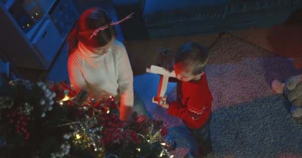 Top uitzicht op de Kaukasische kleine schattige zus en broer versieren kerstboom voor x-mas thuis in de avond. — Stockvideo