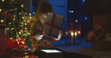 Kafkasyalı güzel bir kızın portresi hediye bir Noel kutusunu açıyor ve Noel gecesi parlarken içeriye bakıyor..