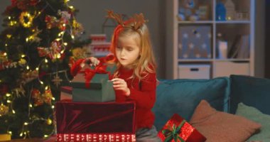 Sarışın, beyaz bir kızın Noel hediyesiyle kutuya bakarken çekilmiş portresi. Noel arifesinde güçlü bir ışık var..