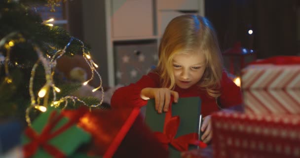 走近一个漂亮的小男孩，他打开一个盒子，看了看丹塔圣诞老人送给他的圣诞礼物. — 图库视频影像