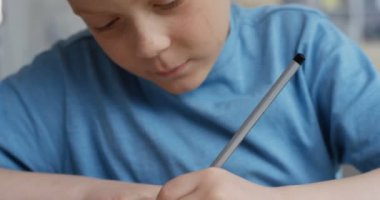 Okulda ders sırasında elinde kalemle yazı yazan ve sınavı düşünen kızıl saçlı çocuğun fotoğrafını çek..