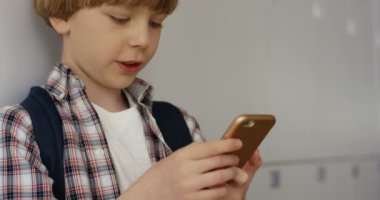 Okullu, küçük, şirin, beyaz bir öğrencinin okul önünde dikilirken telefon dinleyip çene çalmasını..