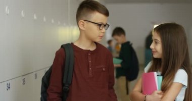 Dost canlısı öğrencilerin portresi, genç okul çocuğu ve okul kızı, birbirlerine bakıp koridorda kameraya gülümsüyorlar..