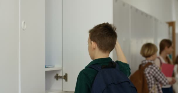 Caucasian teen boy taking out textbooks from his locker and then going away by the school corridor to the lesson. — Stock Video