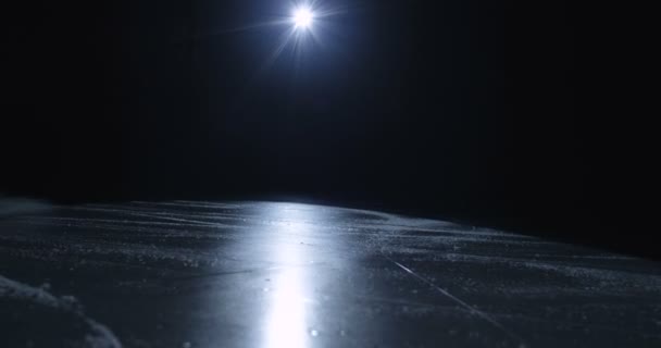 Feche-se do clube que bate no disco na superfície gelada na escuridão. Hockey stick atinge disco na arena de gelo à luz de uma única lâmpada holofote. Conceito de jogo de hóquei. — Vídeo de Stock