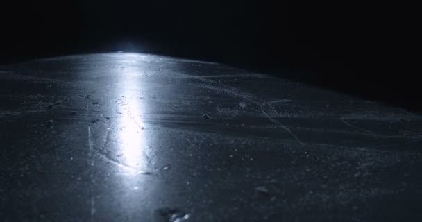 Close-up de pés de jogador hocky ou patinador em patinadores deslizando na superfície gelada na escuridão. Patinar na arena de gelo à luz de uma única lâmpada de holofotes. Conceito de jogo de hóquei. — Vídeo de Stock