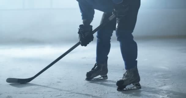 유니폼을 입고 스케이트를 타고 헬멧을 쓴 남자 하키 선수가 얼음 경기장에 서서 경기를 하는 동안 막대기로 토치를 때리는 모습이 묘사되었다. 곤봉을 든 스포츠 선수가 경기중에 얼음에 디스크를 맞다. — 비디오