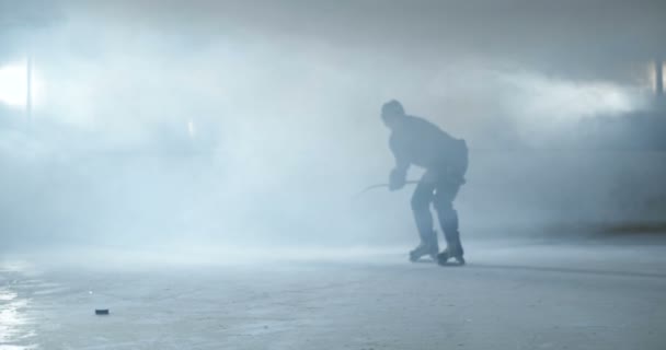 Jogador de hóquei masculino caucasiano de uniforme, patinadores e capacete deslizando rápido na arena gelada e batendo puch com pau durante o jogo. Esportista com patinação clube e bate disco no gelo. — Vídeo de Stock