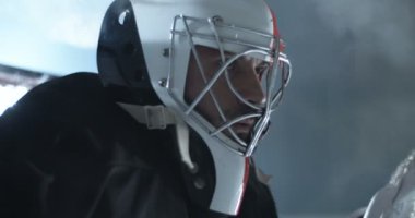 Yakışıklı, beyaz, yakışıklı, yakışıklı erkek hokey oyuncusuna yakın çekim. Buz arenasında oturmuş, bankta bekliyor. Kasklı sporcu.