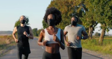 Yazın kırsal yolda koşan melez erkekler ve bayan koşucular. Afrika kökenli, zayıf, sportif kadın ve dışarıda koşan çok ırklı erkekler. Salgın maskeli koşucular.