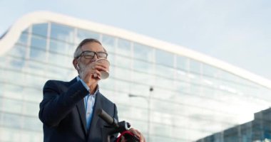 Yaşlı, gri saçlı, gözlüklü ve kulaklıklı bir adam. Bisikletle caddede duruyor ve kahve içiyor. Hava kapsüllerinde müzik dinleyip dışarıda sıcak bir şeyler yudumlayan yaşlı büyükbaba..