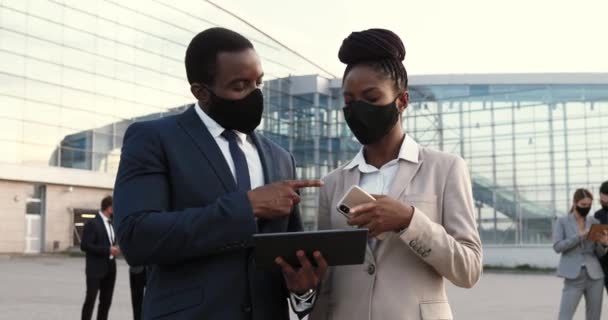 Maskeli birkaç genç Afro-Amerikalı finans merkezinde konuşup tablet cihazı kullanıyor. İş adamı ve iş kadını şehirde sohbet ediyorlar. Salgın. — Stok video
