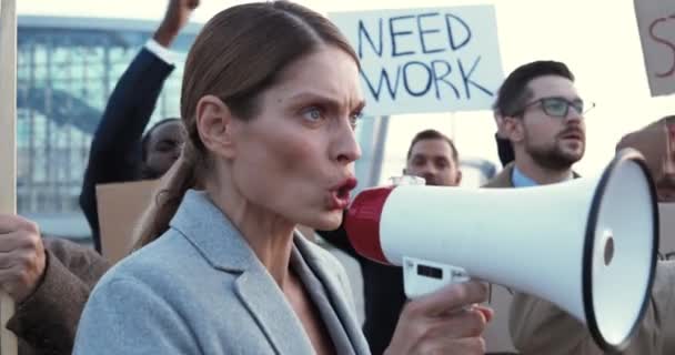 Zblízka běloška krásná žena mluví v megafonu venku na protest proti nezaměstnanosti v multietnickém davu. Ženské projevy ve stávce proti nerovnosti a za lidská práva. — Stock video
