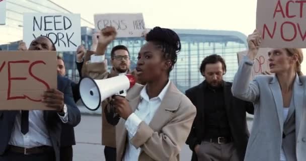 Афроамериканка говорит в мегафоне под открытым небом в знак протеста против безработицы в многонациональной толпе. Женщина-лидер, выступающая на забастовке, и ведущие представители смешанных рас за права человека. — стоковое видео