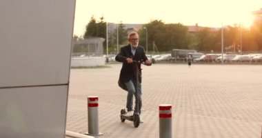 Beyaz saçlı, gözlüklü, elektrikli scooterın üzerinde duran ve bir yerlere giden yaşlı bir adam. Üst düzey emekli ya da işadamı şehir aracını bina girişine sürüyor..