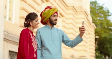 Alnında nokta olan Hindu kadın ve türbanlı adam dışarıda dikiliyor ve akıllı telefondan webcam ile konuşuyor. Videochat. Erkek ve kadın cep telefonuyla görüntülü konuşma. Hızlı video bağlantısı. Ara.