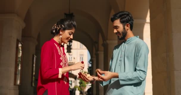 Vrolijk hindoeïstisch jong echtpaar dat betrokken is bij straat en vrouw dragen boeiende ring. Bruiloft in India. Gelukkige man en vrouw in traditionele kleding. — Stockvideo