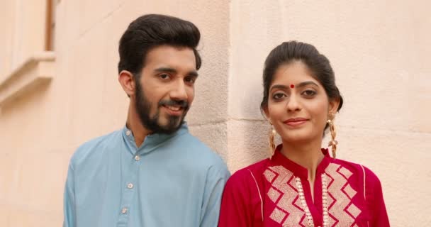 Πορτρέτο όμορφος κομψό νεαρός Ινδουιστής άνδρας και γυναίκα με παραδοσιακά ρούχα αναζητούν και χαμογελώντας στην κάμερα στο δρόμο, ενώ ακουμπά στον τοίχο του κτιρίου. Όμορφο θηλυκό και όμορφο αρσενικό από την Ινδία. — Αρχείο Βίντεο