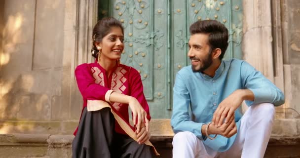 Hindu beautiful woman in traditional outfit and handsome man sitting at street and talking cheerfully. male and female friends speaking and smiling. India concept. Boyfriend and girlfriend on date. — Stock Video