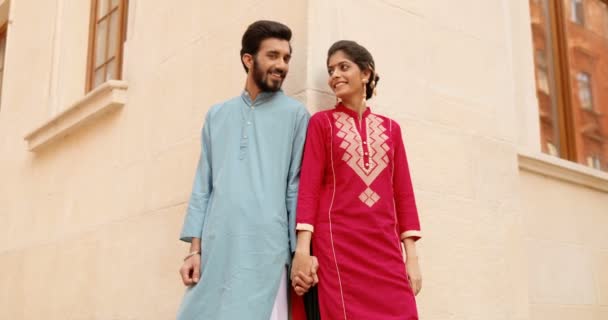 Portrait d'un jeune homme et d'une jeune femme hindous heureux et élégants, vêtus de vêtements traditionnels, la main dans la main, souriant à la caméra dans la rue, s'appuyant sur le mur du bâtiment. Belle femelle et beau mâle. Inde. — Video