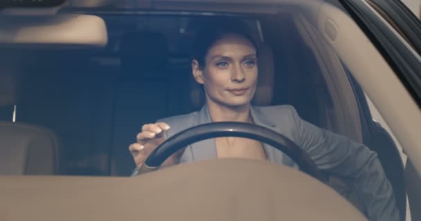 Vista através do pára-brisas. Mulher de negócios bonita sentado no volante em carro caro. Mulher caucasiana atraente saindo do carro. Motorista do sexo feminino deixando automóvel. — Vídeo de Stock