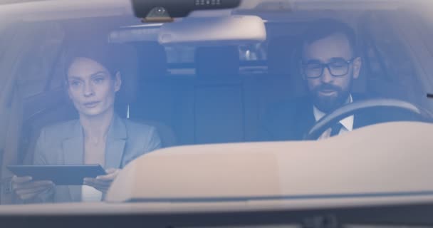 Biały mężczyzna kierujący autem i wyjaśniający coś kobiecie przechodzącej obok niego. Żona i mąż dyskutują i kłócą się. Kobieta z tabletem. Kilku kolegów z pracy w samochodzie. — Wideo stockowe