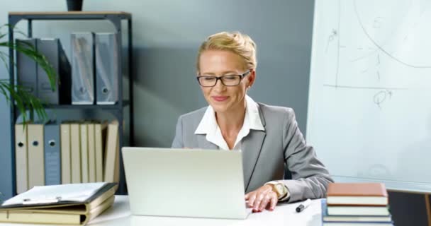 戴眼镜的白人女商人坐在办公室里，在笔记本电脑上通过网络摄像头聊天，视频聊天和教育商界。女教练在网上记录视频博客Blogger视频聊天. — 图库视频影像