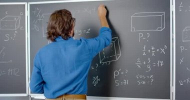 Kafkas erkek okutman matematik ya da fizik formüllerini karatahtaya tebeşirle yazıyor. Erkek öğretmen okulda çalışıyor. Matematik dersi veriyorum. Matematikçi. Geometri ya da cebir denklemi. Arka..