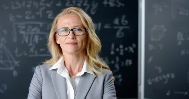 Retrato de sorriu bela professora mulher feliz em óculos. Quadro negro com fórmulas, matemática e leis físicas. Aula de Matemática. Mulher branca a sorrir para a câmara na escola. Conceito de ensino — Vídeo de Stock