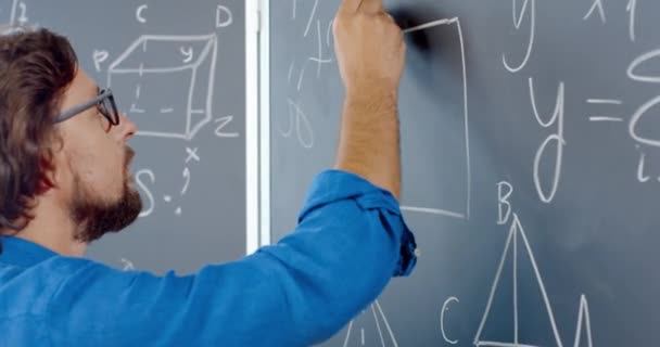 백인 남성 강사가 칠판에 분필로 수학이나 물리 공식을 쓰는 것을 클로즈업 해 보 세요. 남자 교사 학교에서 일하고 있다. 수학에 대한 교훈이죠. 수학자. 기하학이나 대수. — 비디오