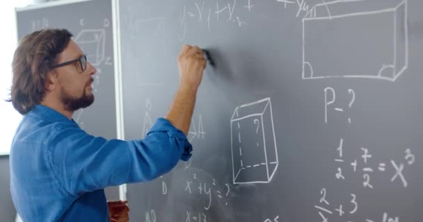 Close-up van blanke mannelijke docent schrijven wiskunde of natuurkunde formules met krijt op schoolbord. Een leraar die op school werkt. Les wiskundekunde. Wiskundige. Geometrie of algebra-vergelijking. — Stockvideo