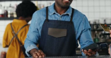 Çoklu etnik çeşitliliğe sahip barmen erkek ve müvekkil kadının ellerini yakın tutun. Beyaz bir kadın maaş kartı ve kredi kartıyla ödeme yapıyor. Karışık ırklar. Ödeme tezgahtan yapılacak. İçki ya da yemek parasını öde. Afrikalı Amerikalı garson
