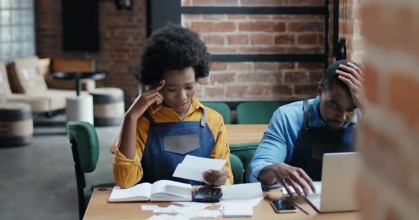 Afro-Amerikalı çift restoran hesaplamaları yapıyor ve faturaları kontrol ediyor. Harcamalar ve kafedeki hasarlar hesaplanıyor. Dizüstü bilgisayardaki kilitleme işleminden sonra yeniden aç Küçük girişimcilik. — Stok video