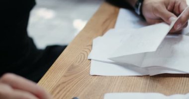 Masada oturan ve iş hesaplamaları yapan beyaz adamın ellerini yakın çekim. Harcamaları ve kafelerin zararlarını hesaplayan bir adam. Tecritten sonra tekrar açın. Hesap makinesinde sayıyorum. Küçük girişimcilik..