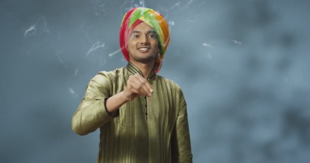 伝統的なターバンで幸せなハンサムなヒンドゥ教徒の若い男がカメラに笑みを浮かべて、臭いとインドのお香スティックを保持。ジョス棒で手を振る男の肖像画。文化的伝統概念. — ストック動画