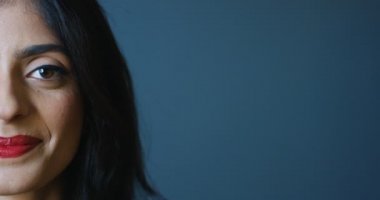 Mutlu Hindu genç bayanın yüzünün yarısını kapatın. Kırmızı dudaklı, gri arka plandaki kameraya neşeyle gülümseyen güzel bir kadın. Hindistan 'da güzel bir kadının portresi..