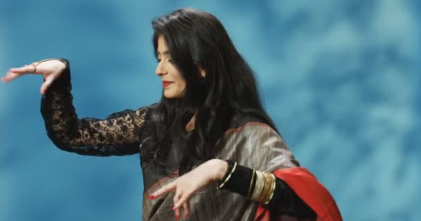 Молода індуська вродлива жінка в традиційному барвистому одязі танцює й махає руками. Індійська весела танцівниця усміхається й ніжно рухається.. — стокове відео