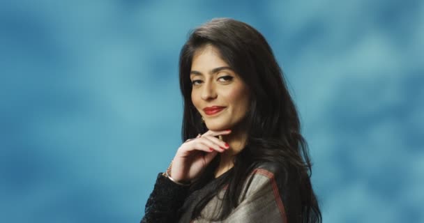 Portrait de jeune hindoue belle femme joyeuse dans un look traditionnel souriant à la caméra sur fond bleu. Charmante fille élégante avec sourire dans le style indien. — Video