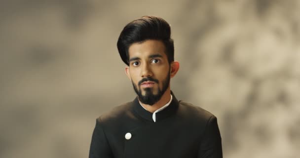 Portret van een jonge knappe Hindoe man met baard en in zwart jasje kijkend naar de camera. close-up van Indiaas aantrekkelijk man. — Stockvideo