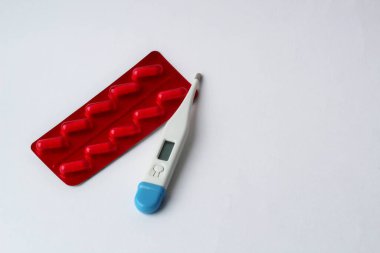 Beyaz arka planda haplar ve termometre.