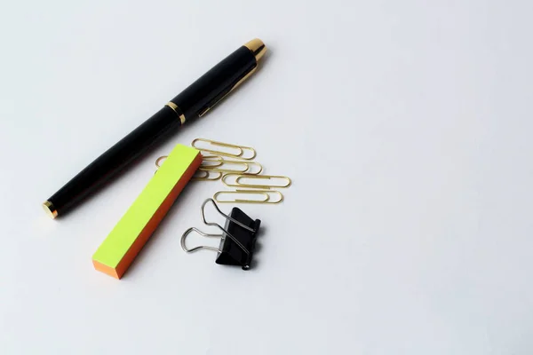 pen for writing and paper clip on a white background